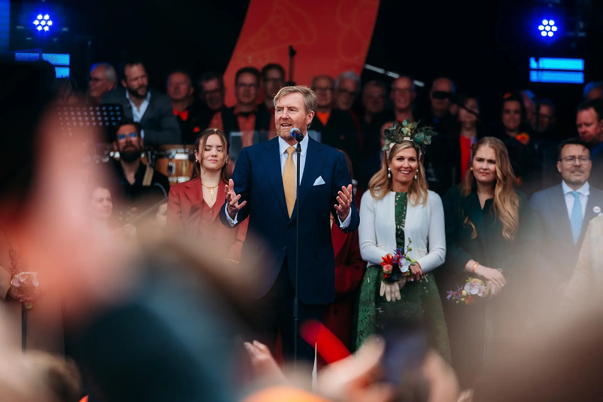 De koning en koningin op een podium in Emmen, omringd door publiek